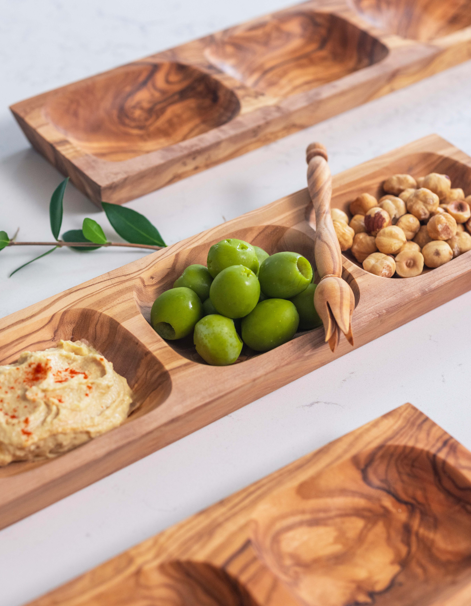 Three Apero wood platters made in Tunisia serving hazelnuts, humus and Castrelvetrano olives