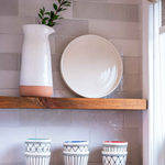 Shelves showcasing off white ceramic platter, pitcher and tumblers