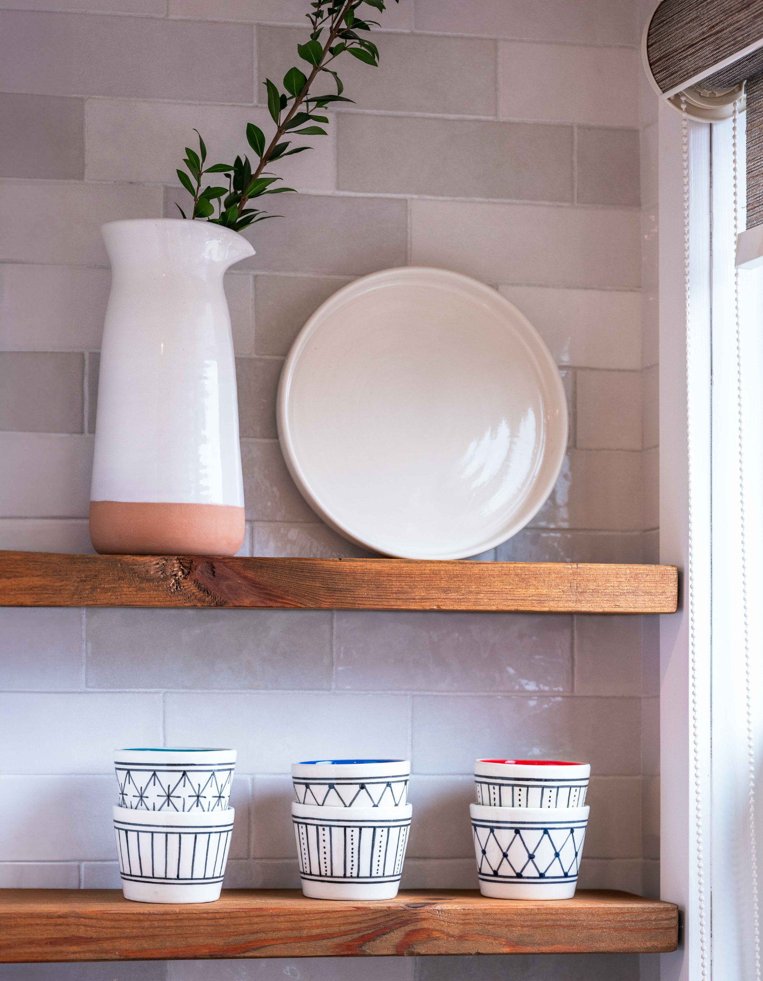 Shelves showcasing off white ceramic platter, pitcher and tumblers