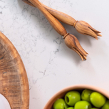 Chad pick olives on marble near a ceramic bowl of olives and olive wood plate Dora