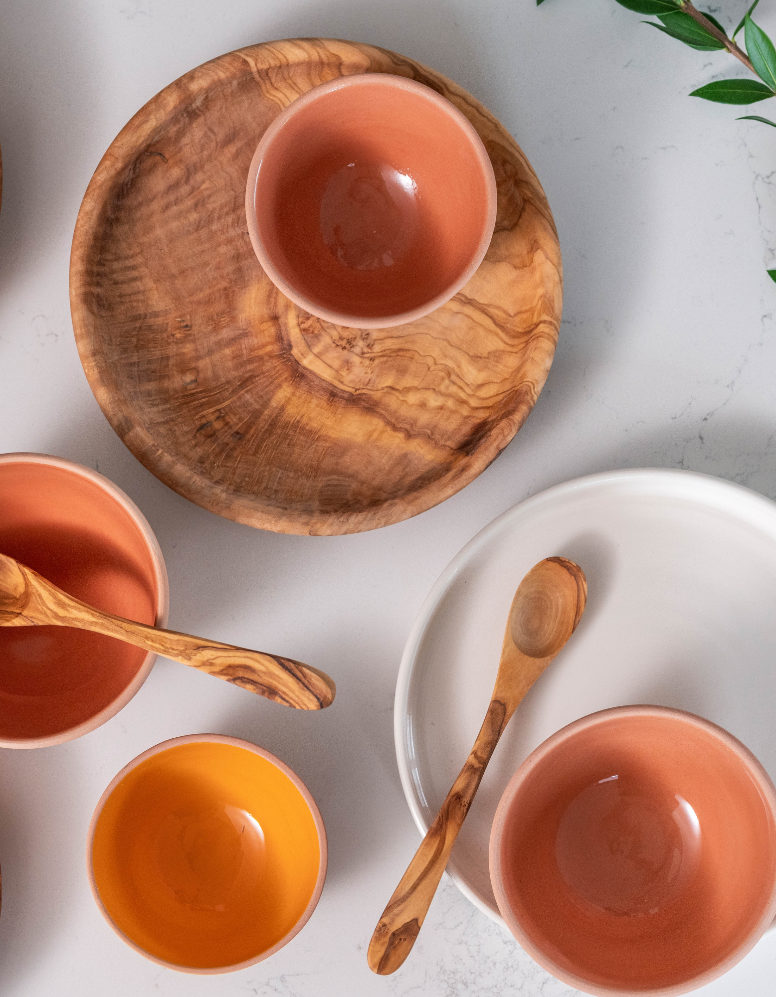 Assortment of ceramic bowl and wooden plate on white quartz countertop